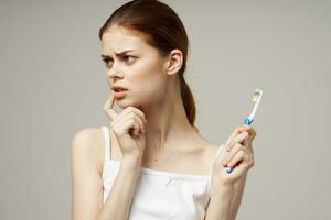 alegre mulher com uma escova de dente dentro mão manhã higiene isolado fundo foto