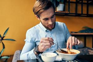 homem comendo almoço às cafeteria mesa pausa às trabalhos e interior foto