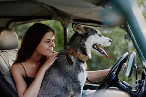 mulher e dela rouco cachorro alegremente viajando dentro carro sorrir com dentes outono andar com bicho de estimação, viagem com cachorro amigo foto