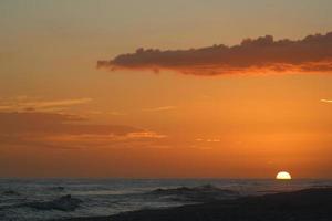 de praia pôr do sol com alguns nuvens pessoas silhueta foto