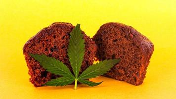 folha de cannabis e bolo doce em fundo amarelo foto
