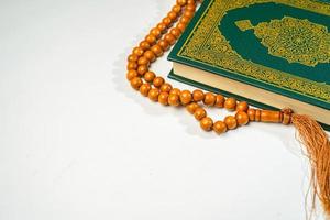 a piedosos al Alcorão com escrito árabe caligrafia significado do al Alcorão e rosário miçangas ou tasbih em branco fundo com cópia de espaço. foto