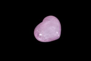 coração de pedra mineral macro quartzo rosa em um fundo preto foto