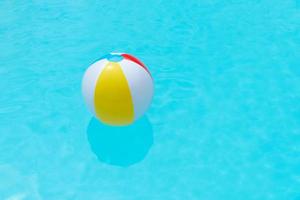 bola de praia flutuando na superfície da água de uma piscina foto