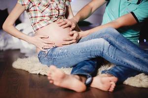 jovem casal esperando bebê abraçando a barriga. gravidez e conceito de pessoas foto