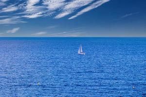 calma azul beira-mar panorama com água e céu e veleiros foto