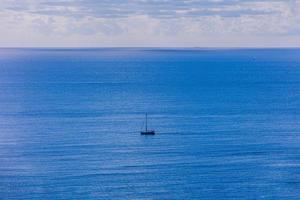 calma azul beira-mar panorama com água e céu e veleiros foto