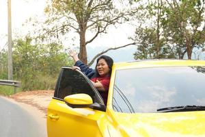 meia idade ásia mulher com dela Amado amarelo sedan feliz brilhante sorrir para viagem a montanhas em uma verão período de férias. suave e seletivo foco. foto