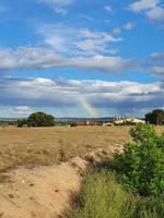 verão rural panorama em uma verão dia com uma colorida arco Iris dentro a azul céu foto