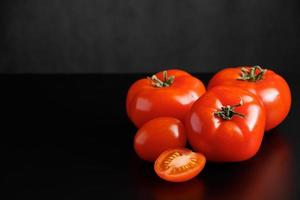 tomates vermelhos maduros em um fundo preto foto