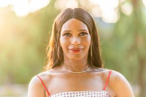 retrato do uma sorridente transgêneros mulher dentro uma parque foto