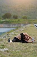 jovem menina fazendo ioga ginástica exercício manhã nascer do sol ao ar livre dentro a Prado lindo montanhas panorama. meditação e relaxar. foto