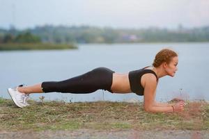 jovem menina fazendo ioga ginástica exercício manhã nascer do sol ao ar livre dentro a Prado lindo montanhas panorama. meditação e relaxar. foto