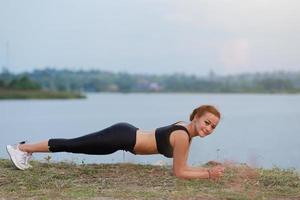 jovem menina fazendo ioga ginástica exercício manhã nascer do sol ao ar livre dentro a Prado lindo montanhas panorama. meditação e relaxar. foto