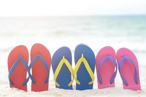 mar na praia pegada pessoas na areia e chinelo de pés em sandálias sapatos em fundo de areias de praia. conceito de férias de viagem. foto