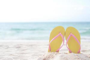 mar na praia pegada pessoas na areia e chinelo de pés em sandálias sapatos em fundo de areias de praia. conceito de férias de viagem. foto