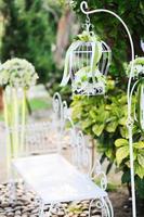 branco gaiola, cadeira decoração com rosas e branco flores suspensão decoração dentro jardim para Casamento cerimônia foto