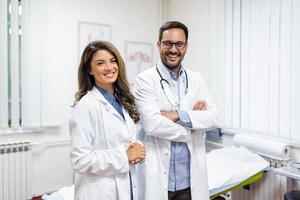 retrato do sorridente jovem médicos em pé junto. retrato do médico funcionários dentro moderno hospital sorridente para Câmera foto