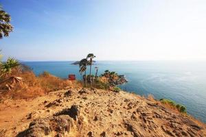 Cuidado escorregadio Atenção placa em Rocha montanha capa.linda marinha com pôr do sol e Palma árvore em seco Relva campo em montanha do phrom então capa dentro phuket ilha, tailândia. foto