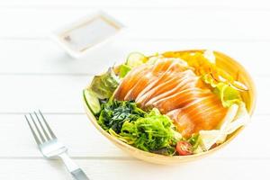 Salmão cru fresco sashimi de carne de peixe com salada de algas e outros vegetais foto