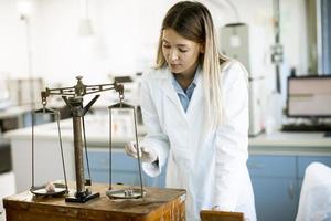 jovem pesquisadora medindo o peso da amostra mineral no laboratório foto