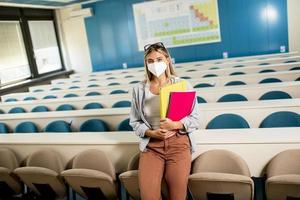 aluna usando máscara médica protetora facial para proteção contra vírus em pé na sala de aula foto