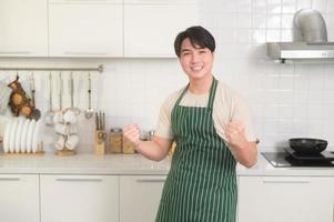 retrato do inteligente jovem ásia homem sorridente dentro cozinha às casa foto