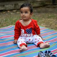 fofa pequeno indiano infantil sentado desfrutando ao ar livre tiro às sociedade parque dentro Délhi, fofa bebê Garoto sentado em colorida esteira com Relva em volta, bebê Garoto ao ar livre tiro foto