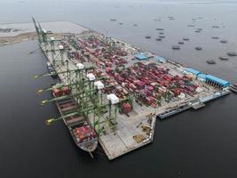 Jacarta, Indonésia 2021- vista aérea do carregamento e descarregamento de um navio de contêiner em um porto de alto mar, transporte de carga de importação e exportação foto
