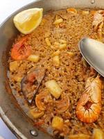 quente espanhol paella com frutos do mar e camarão e uma colher foto