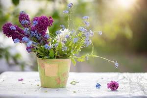 Primavera ou verão fundo. uma ramalhete do flores silvestres dentro a velho vaso de flores aceso de luz solar. lindo flores em uma verde fundo. foto