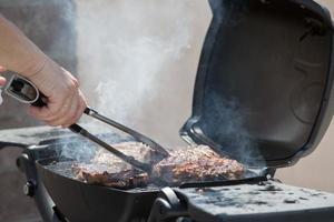 a mão é girando sobre a grelhado eu no. cozinhando churrasco eu no. foto