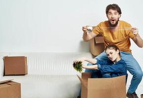 jovem casado casal dentro uma Novo apartamento em uma branco sofá caixas com coisas comovente foto