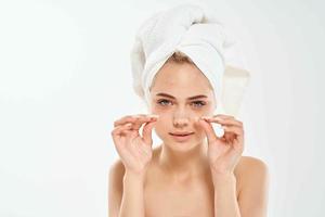 mulher segurando face com toalha em cabeça limpar \ limpo pele dermatologia foto