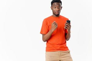 surpreso homem africano aparência com telefone dentro mãos estúdio cortada Visão foto