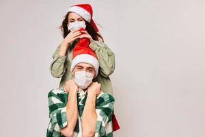 feliz mulher em a costas do uma homem dentro uma médico mascarar e Natal Novo ano saúde foto