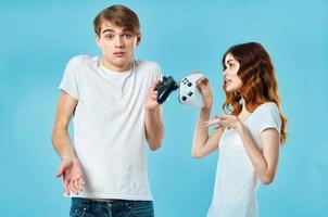 jovem casal camiseta com joysticks dentro mãos vídeo jogos tecnologia azul fundo foto
