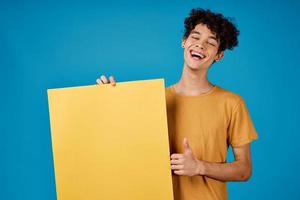 cara com encaracolado cabelo do amarelo ásteres dentro dele mãos estúdio azul fundo foto