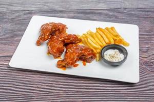 quente e picante búfalo frango asas e crocantes francês fritas com branco molho. foto