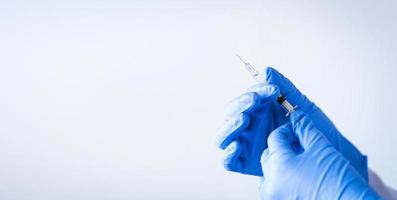 close-up das mãos da enfermeira segurando a vacina com luvas azuis