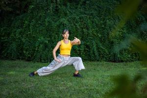 uma mulher práticas tai chi dentro uma parque. praticando ao ar livre fornece uma calma e relaxante meio Ambiente para meditação e concentração. foto