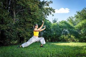 sereno adulto mulher fazendo qigong exercício dentro a parque. conexão para natureza e a vital energia do a universo. foto