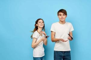 alegre jovem casal dentro branco Camisetas telefones dentro mãos comunicação estilo de vida foto