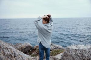 bonita mulher blusas nublado mar admirando natureza estilo de vida costas Visão foto