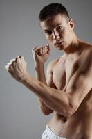 retrato do boxer com muscular corpo em cinzento fundo mãos dentro punho foto