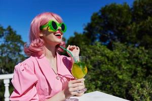 Deleitado jovem menina dentro verde oculos de sol com coquetel dentro verão ao ar livre verão dia foto