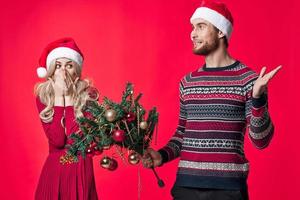 uma homem com uma Natal árvore dentro dele mãos Próximo para uma mulher emoções feriado decoração foto