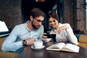 o negócio casal sentado às uma mesa dentro uma cafeteria café da manhã comunicação trabalhos foto