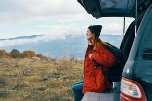 mulher caminhante dentro caloroso roupas em repouso dentro a outono dentro a montanhas perto a carro foto