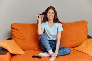 lindo mulher conversando em a laranja sofá com uma Smartphone apartamentos foto